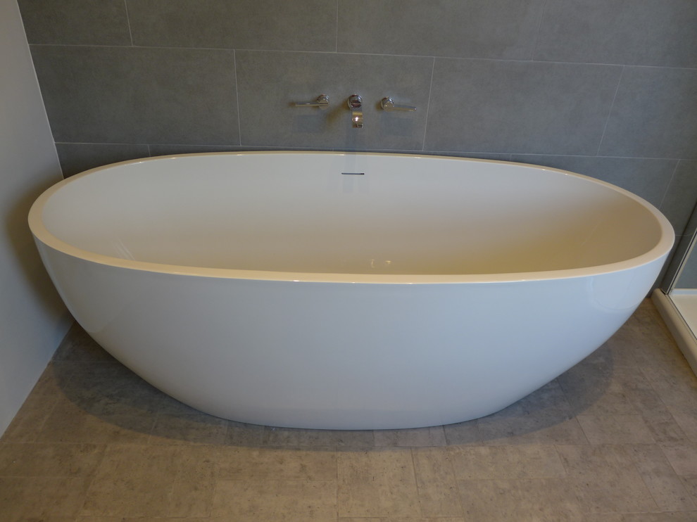 Idées déco pour une salle de bain principale contemporaine de taille moyenne avec une baignoire indépendante, un carrelage gris, des carreaux de porcelaine, un mur gris et un sol en linoléum.