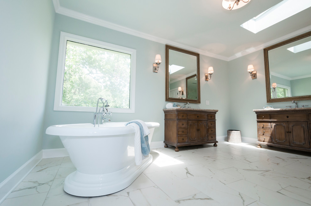 Klassisk inredning av ett stort en-suite badrum, med ett undermonterad handfat, möbel-liknande, skåp i mellenmörkt trä, granitbänkskiva, ett fristående badkar, en öppen dusch, en toalettstol med hel cisternkåpa, porslinskakel, blå väggar och klinkergolv i porslin