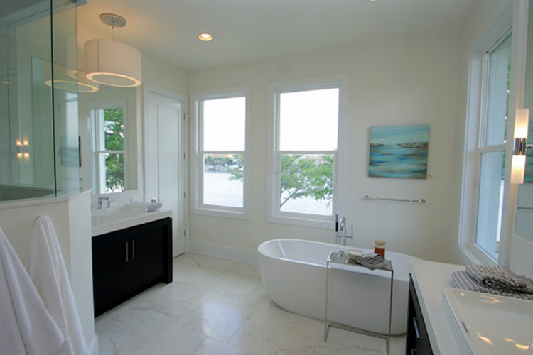 Photo of a large modern ensuite bathroom in Tampa with a vessel sink, dark wood cabinets, a freestanding bath, white walls, marble flooring, a corner shower, quartz worktops and white floors.