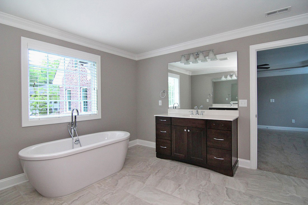 Bathroom - large traditional master ceramic tile and white floor bathroom idea in Raleigh with recessed-panel cabinets, dark wood cabinets, a one-piece toilet, gray walls, a hinged shower door and white countertops