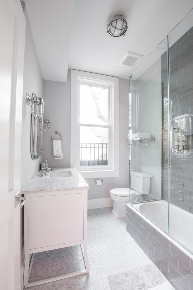 Immagine di una piccola stanza da bagno classica con lavabo a consolle, top in marmo, vasca ad alcova, vasca/doccia, WC a due pezzi, piastrelle grigie, piastrelle di vetro, pareti grigie e pavimento in marmo