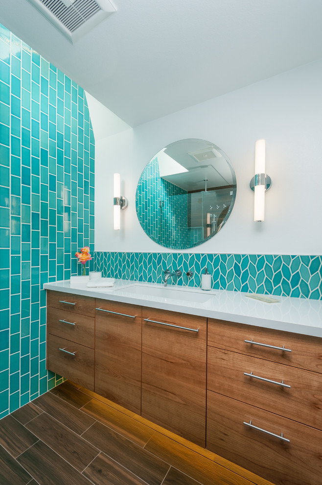 Cette photo montre une salle de bain principale tendance en bois brun de taille moyenne avec un placard à porte plane, WC à poser, des carreaux de céramique, un mur blanc, un sol en carrelage de porcelaine, un lavabo encastré, un plan de toilette en quartz modifié et un carrelage bleu.