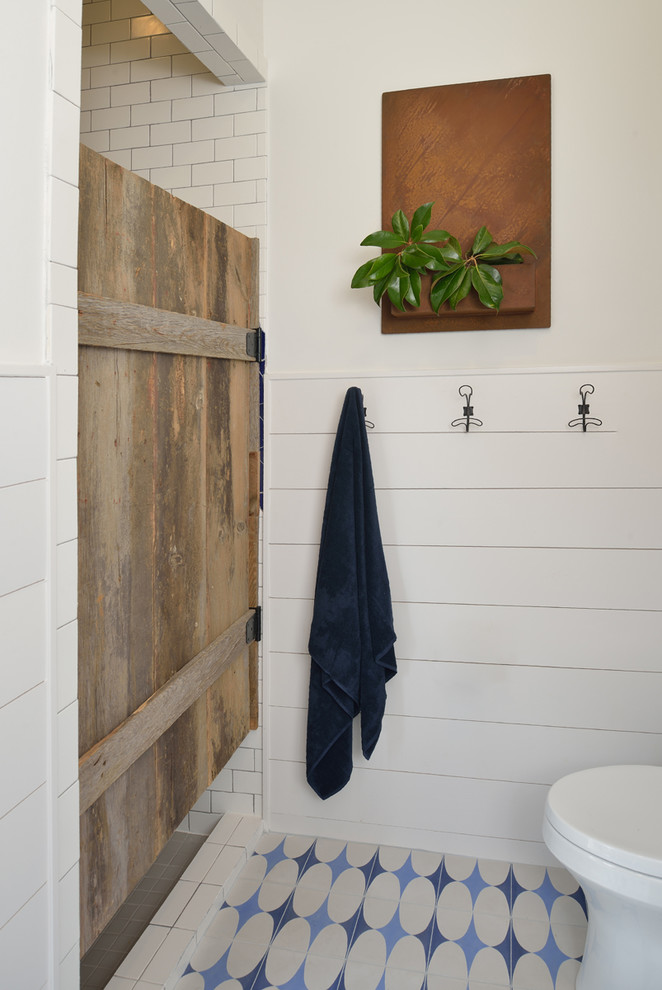 Inredning av ett lantligt stort badrum med dusch, med en dusch i en alkov, vit kakel, keramikplattor, vita väggar, klinkergolv i keramik, blått golv och dusch med gångjärnsdörr