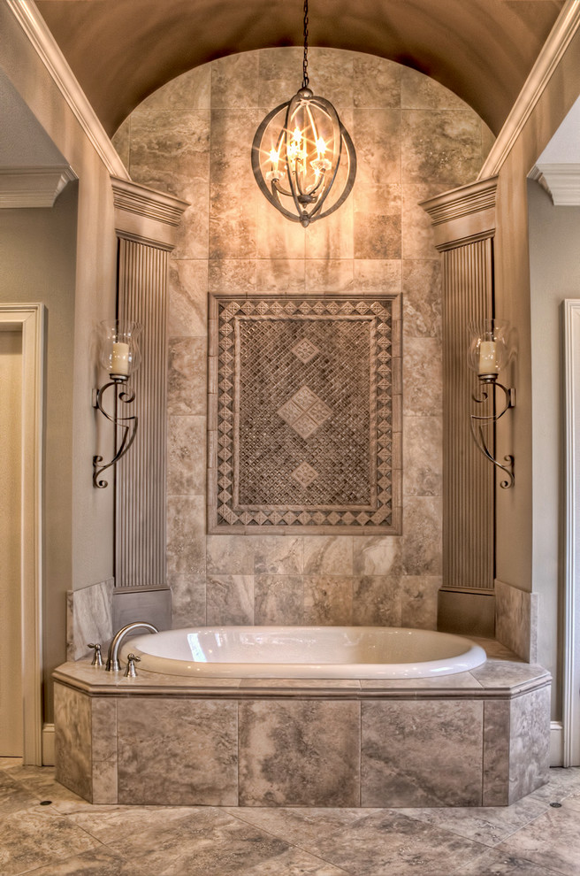 Inredning av ett stort en-suite badrum, med ett fristående handfat, luckor med profilerade fronter, skåp i mellenmörkt trä, granitbänkskiva, ett platsbyggt badkar, beige kakel, porslinskakel, klinkergolv i porslin och grå väggar