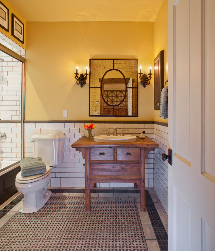 Example of a mid-sized farmhouse 3/4 white tile and stone tile marble floor bathroom design in Denver with furniture-like cabinets, medium tone wood cabinets, a two-piece toilet, yellow walls, a drop-in sink and wood countertops
