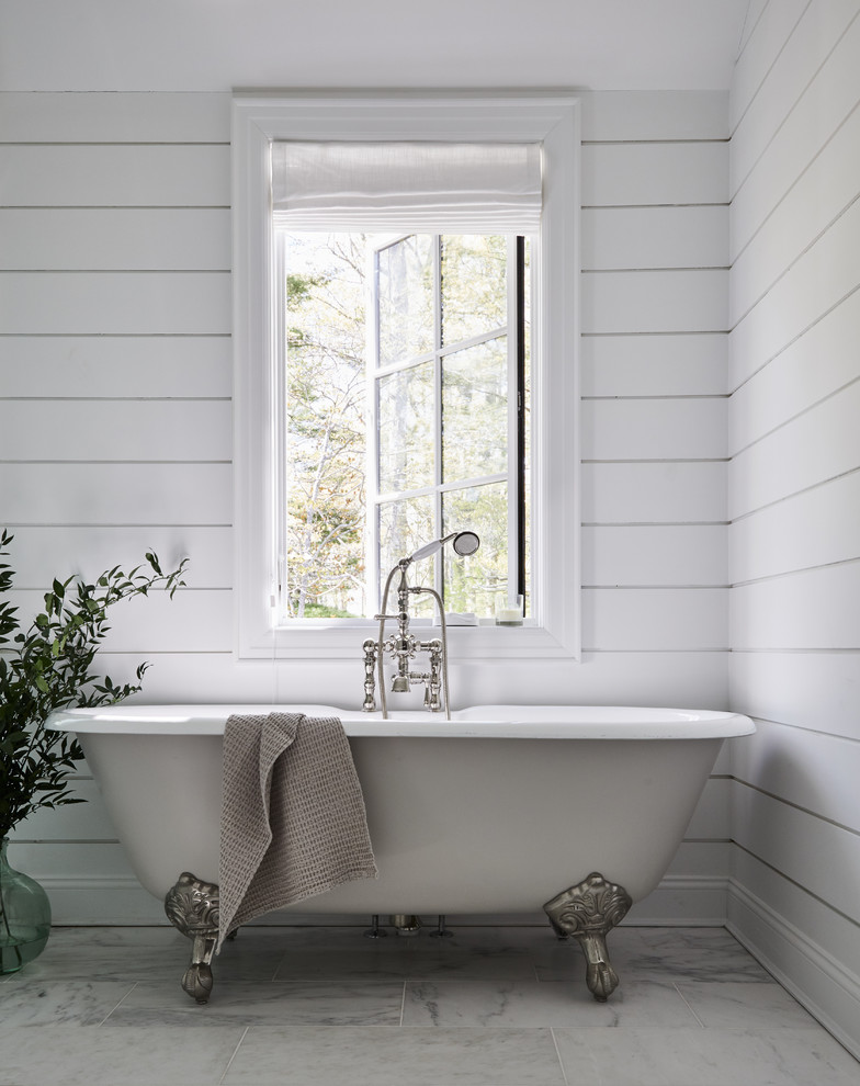 На фото: ванная комната в стиле кантри с ванной на ножках, белыми стенами и белым полом с