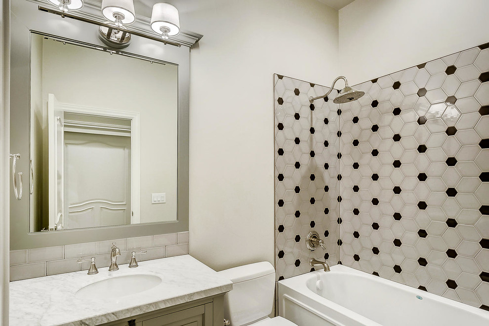 Cette image montre une salle d'eau de taille moyenne avec un placard avec porte à panneau encastré, des portes de placard grises, une baignoire en alcôve, un combiné douche/baignoire, WC séparés, un carrelage gris, des carreaux de céramique, un mur blanc, carreaux de ciment au sol, un lavabo posé, un plan de toilette en marbre, un sol multicolore, une cabine de douche avec un rideau et un plan de toilette blanc.
