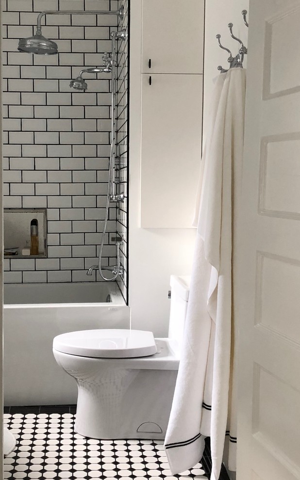На фото: главная ванная комната среднего размера в стиле неоклассика (современная классика) с плоскими фасадами, белыми фасадами, ванной в нише, душем над ванной, унитазом-моноблоком, белой плиткой, плиткой кабанчик, белыми стенами, полом из керамической плитки, стеклянной столешницей, разноцветным полом и шторкой для ванной с