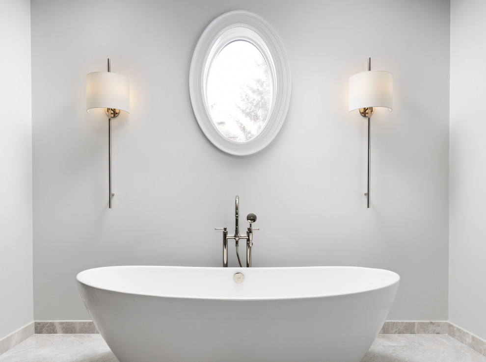 Foto på ett mycket stort vit en-suite badrum, med möbel-liknande, bruna skåp, ett fristående badkar, en dubbeldusch, en toalettstol med hel cisternkåpa, vit kakel, marmorkakel, vita väggar, marmorgolv, ett undermonterad handfat, marmorbänkskiva, grått golv och dusch med gångjärnsdörr