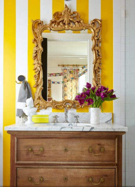 Cette photo montre une salle de bain chic en bois clair avec un lavabo de ferme, un placard en trompe-l'oeil, un plan de toilette en marbre, un carrelage blanc et un mur jaune.