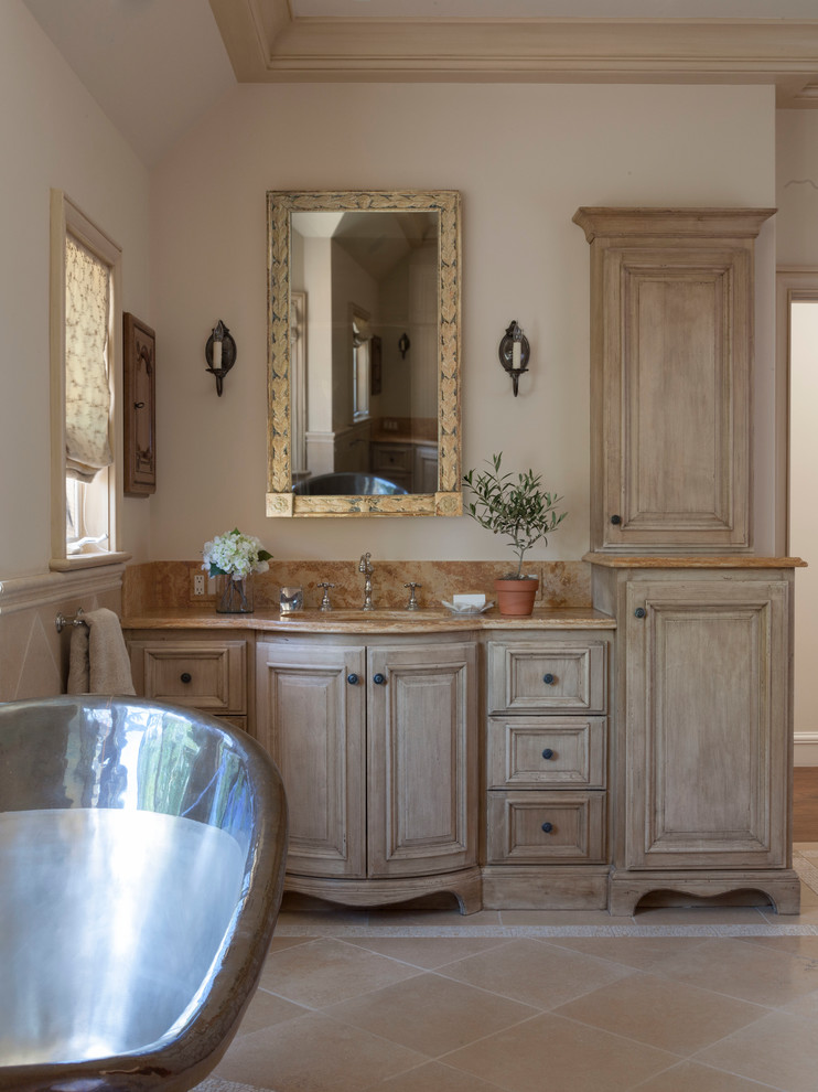 Diseño de cuarto de baño principal clásico extra grande con armarios tipo mueble, puertas de armario de madera clara, encimera de mármol, bañera exenta, paredes beige y suelo de baldosas de cerámica
