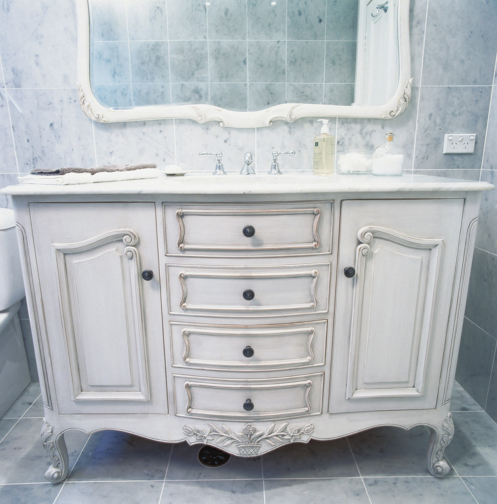 Стильный дизайн: ванная комната среднего размера в классическом стиле с белыми фасадами, полновстраиваемой ванной, раздельным унитазом, серой плиткой, серыми стенами, врезной раковиной, мраморной столешницей и серым полом - последний тренд