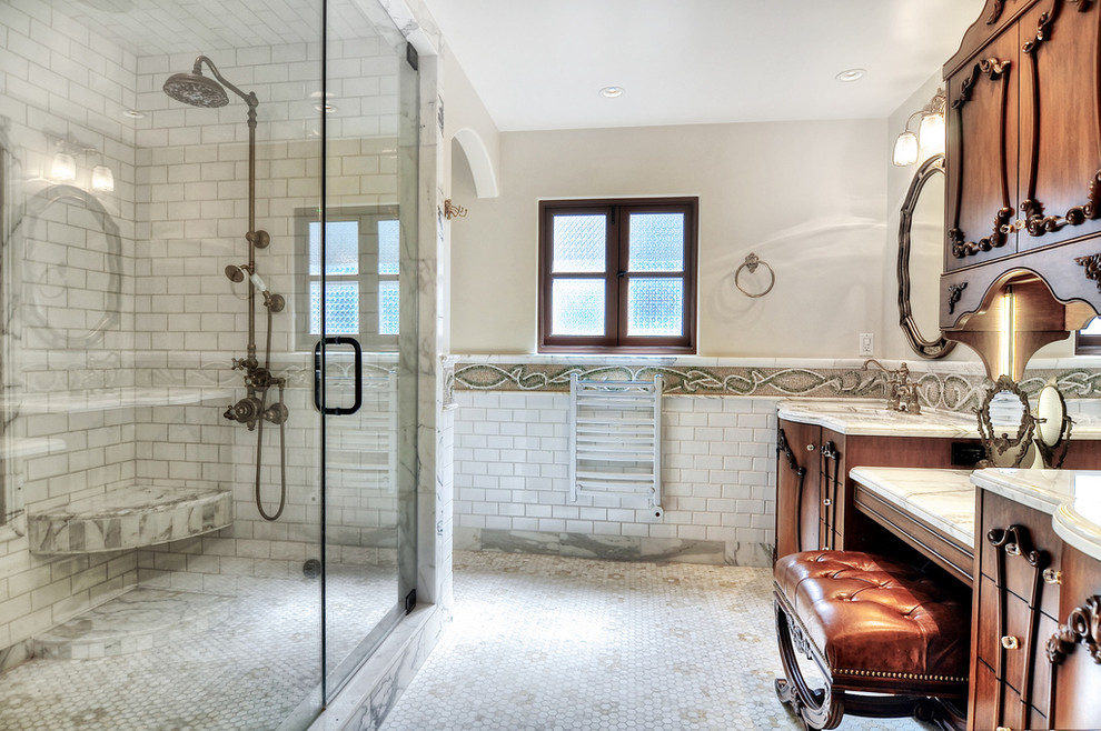 Cette photo montre une salle d'eau méditerranéenne en bois brun de taille moyenne avec un placard avec porte à panneau surélevé, une baignoire d'angle, une douche à l'italienne, WC à poser, un carrelage multicolore, mosaïque, un mur gris, parquet clair, un lavabo encastré et un plan de toilette en granite.