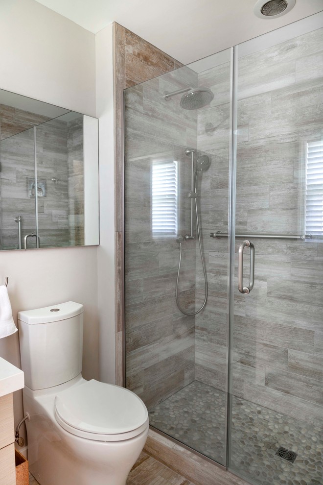 Exemple d'une petite salle de bain principale bord de mer avec un lavabo encastré, un placard à porte plane, WC à poser, des carreaux de porcelaine, un mur gris, un sol en carrelage de porcelaine et un carrelage gris.