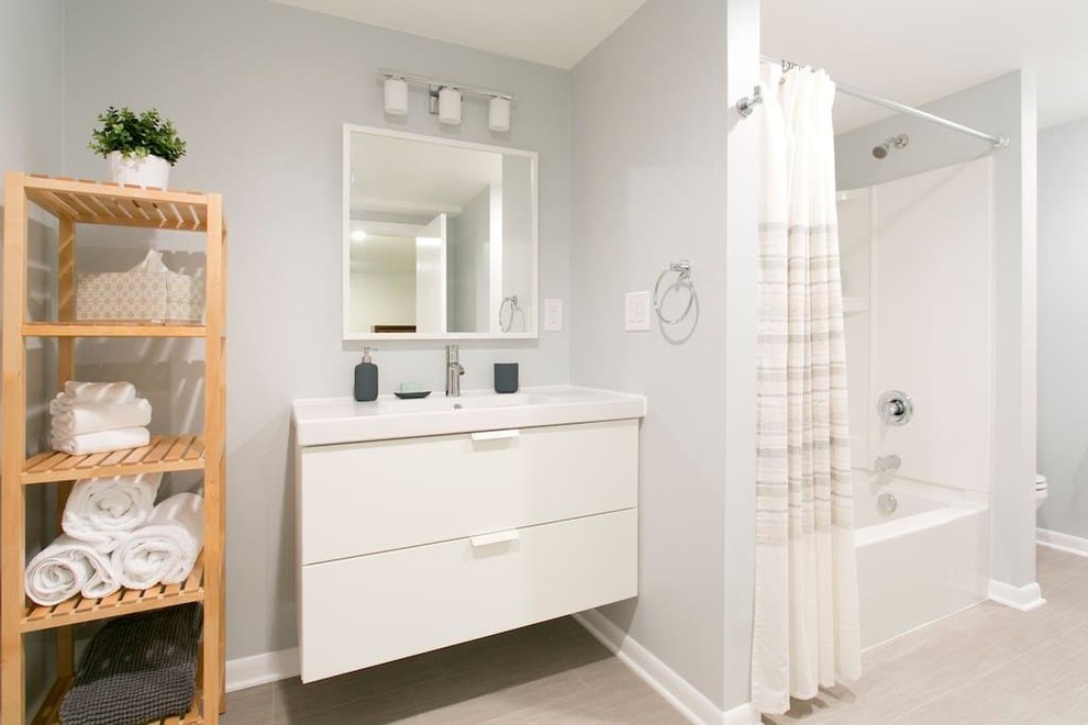 Exemple d'une douche en alcôve chic avec une baignoire en alcôve, un mur gris, un plan vasque, un placard à porte plane, des portes de placard blanches et une cabine de douche avec un rideau.