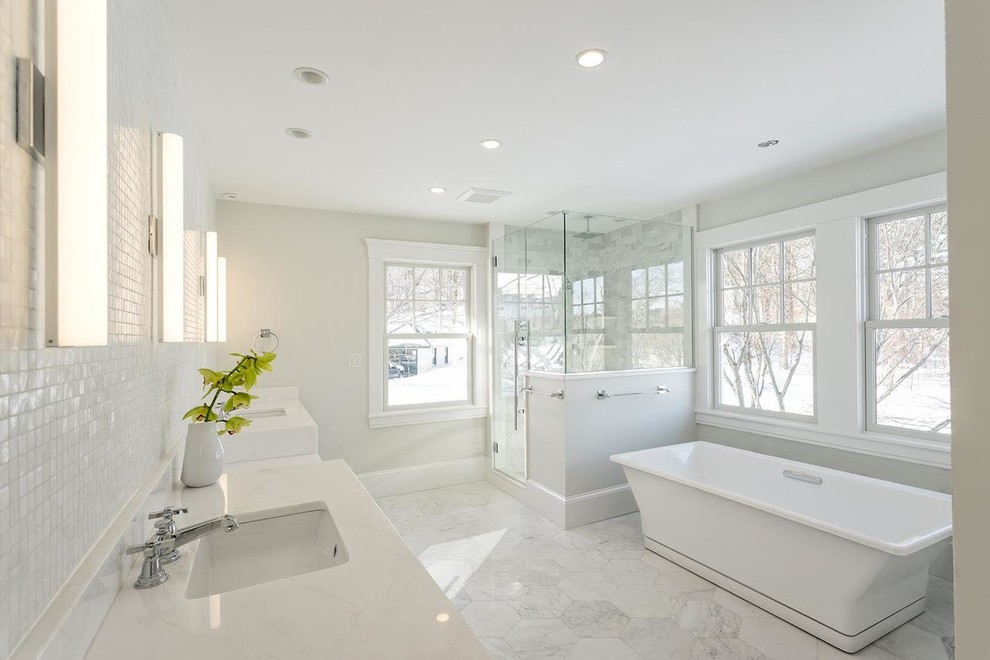 Стильный дизайн: большая главная ванная комната в стиле неоклассика (современная классика) с белыми фасадами, отдельно стоящей ванной, угловым душем, серой плиткой, плиткой из листового стекла, белыми стенами, полом из керамогранита, врезной раковиной, серым полом, душем с распашными дверями, белой столешницей и фасадами с утопленной филенкой - последний тренд