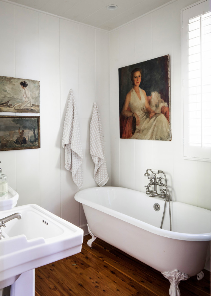 На фото: главная ванная комната среднего размера в скандинавском стиле с ванной на ножках, белыми стенами, раковиной с пьедесталом, коричневым полом, темным паркетным полом, тумбой под две раковины и стенами из вагонки с