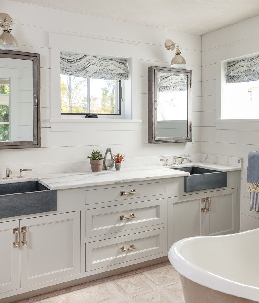 Inspiration for a farmhouse bathroom in Boston with recessed-panel cabinets, white cabinets, a freestanding bath, white walls, beige floors and white worktops.