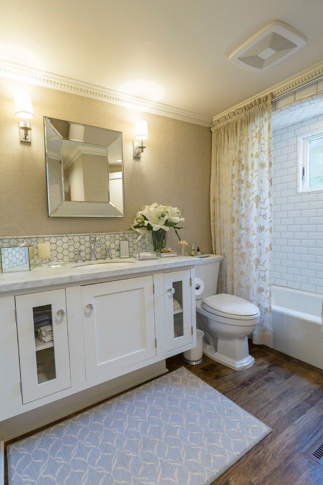 Klassisches Badezimmer mit weißen Schränken, beiger Wandfarbe, dunklem Holzboden und Marmor-Waschbecken/Waschtisch in Sonstige