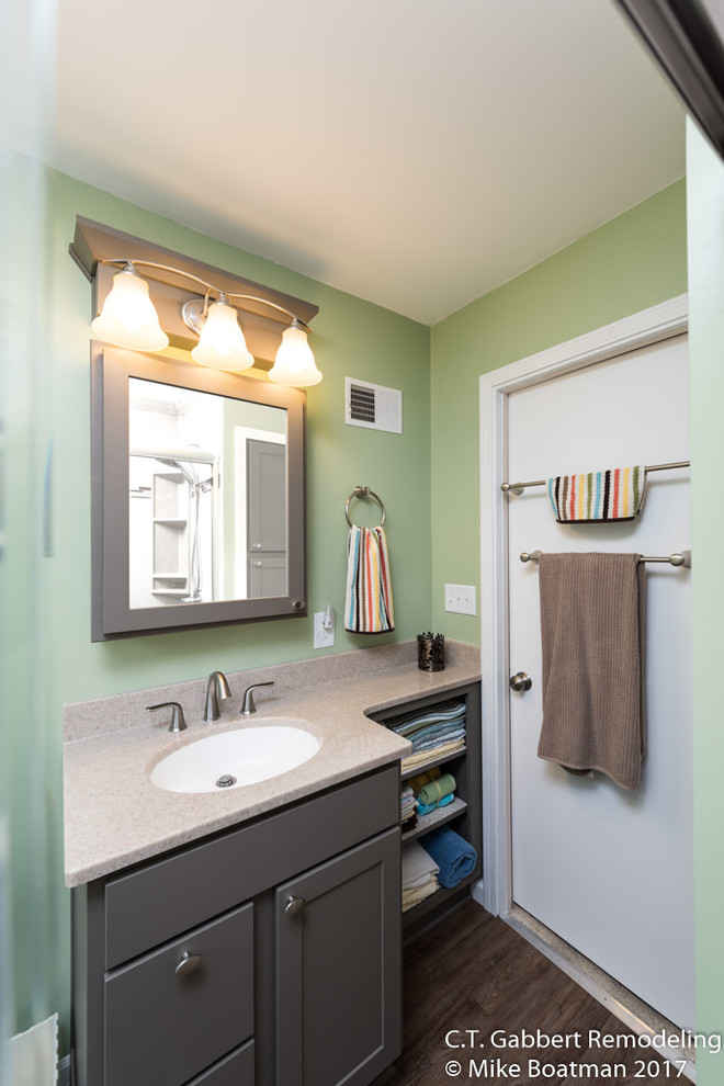 Klassisk inredning av ett litet badrum med dusch, med luckor med infälld panel, grå skåp, en dusch i en alkov, flerfärgade väggar, laminatgolv, ett integrerad handfat, bänkskiva i onyx, brunt golv och dusch med skjutdörr