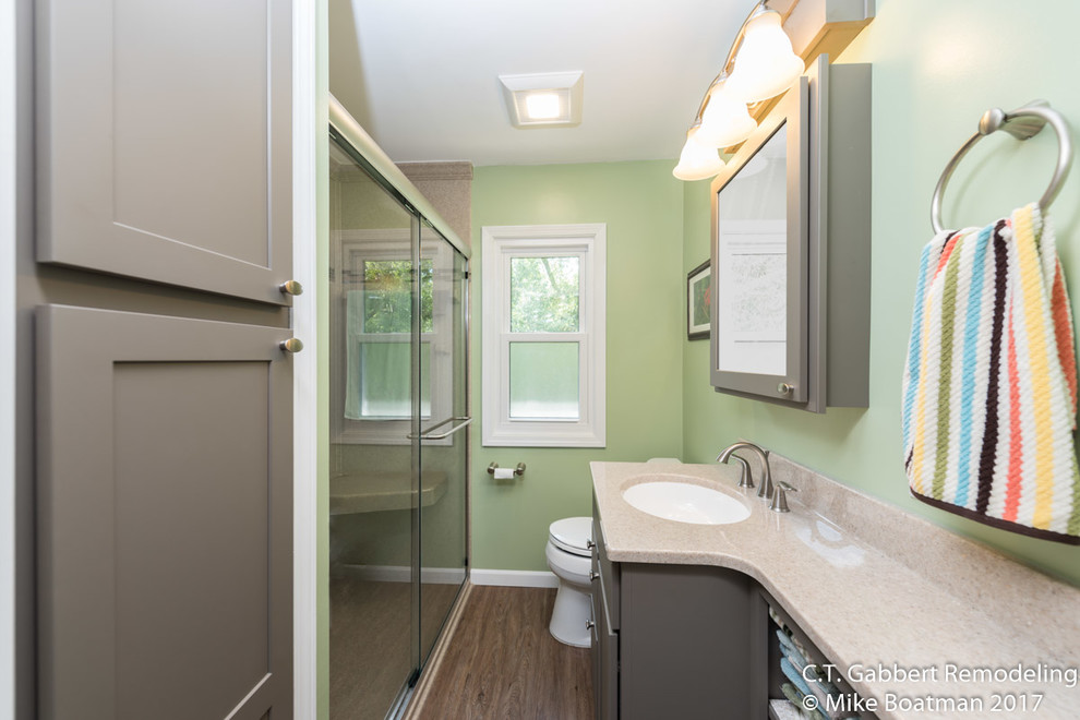 На фото: маленькая ванная комната в стиле неоклассика (современная классика) с фасадами с утопленной филенкой, серыми фасадами, душем в нише, разноцветными стенами, полом из ламината, душевой кабиной, монолитной раковиной, столешницей из оникса, коричневым полом и душем с раздвижными дверями для на участке и в саду с