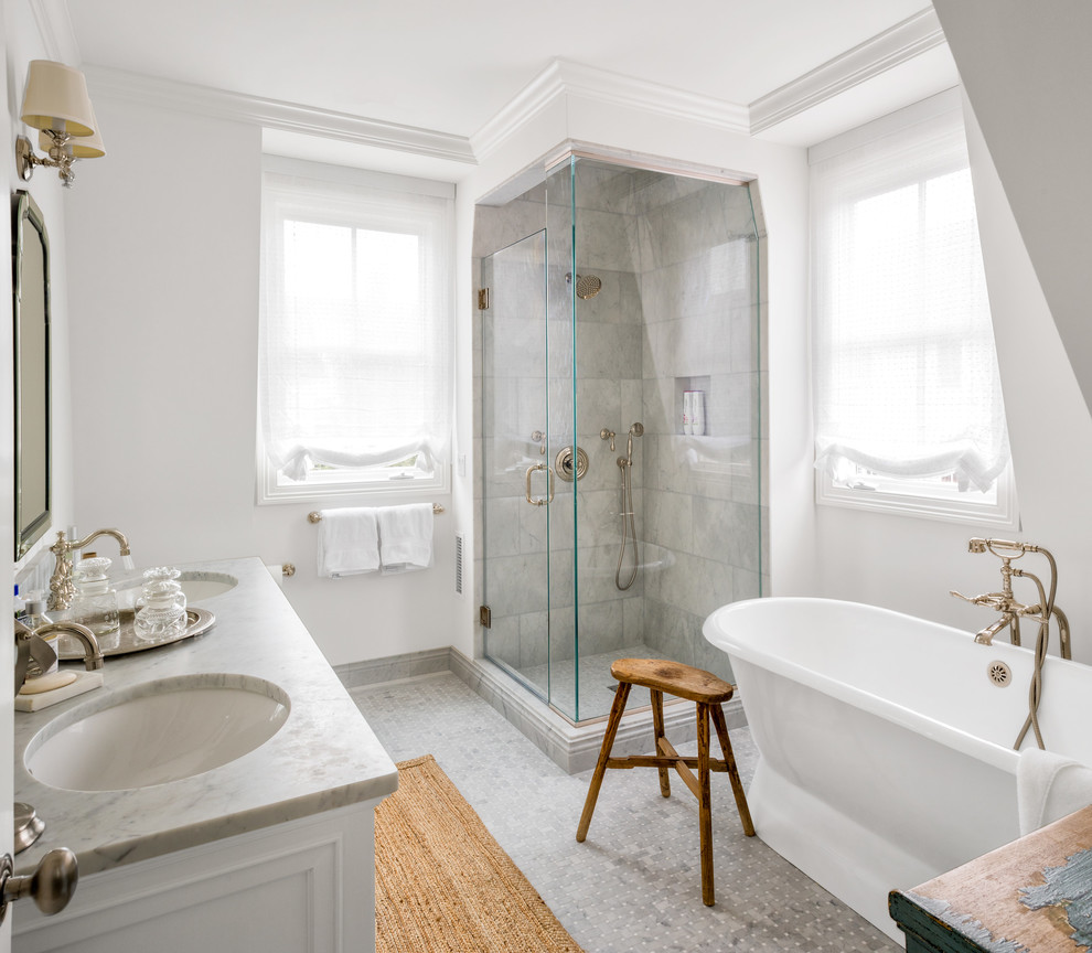 Inspiration for a classic ensuite bathroom in New York with shaker cabinets, white cabinets, a freestanding bath, a corner shower, grey tiles, white walls, a submerged sink, grey floors and a hinged door.