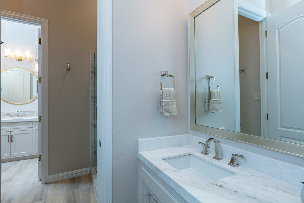 Стильный дизайн: ванная комната среднего размера в стиле неоклассика (современная классика) с фасадами с утопленной филенкой, бежевыми фасадами, раздельным унитазом, белой плиткой, мраморной плиткой, бежевыми стенами, полом из керамогранита, врезной раковиной, мраморной столешницей, бежевым полом, душем с распашными дверями и белой столешницей - последний тренд