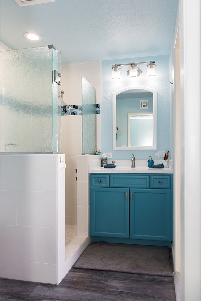 Inspiration pour une petite salle de bain principale traditionnelle avec un placard à porte shaker, des portes de placard bleues, une baignoire en alcôve, une douche d'angle, WC à poser, un carrelage gris, des carreaux de porcelaine, un mur blanc, sol en stratifié, un lavabo encastré, un plan de toilette en quartz modifié, un sol gris, une cabine de douche à porte battante et un plan de toilette blanc.