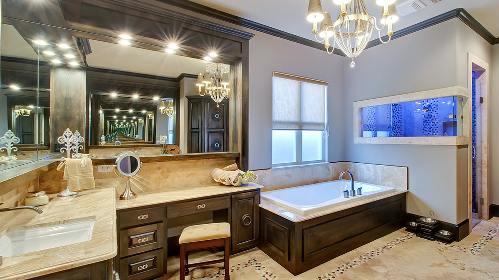 На фото: ванная комната в классическом стиле с врезной раковиной, фасадами с выступающей филенкой, темными деревянными фасадами, бежевой плиткой, накладной ванной и фартуком с