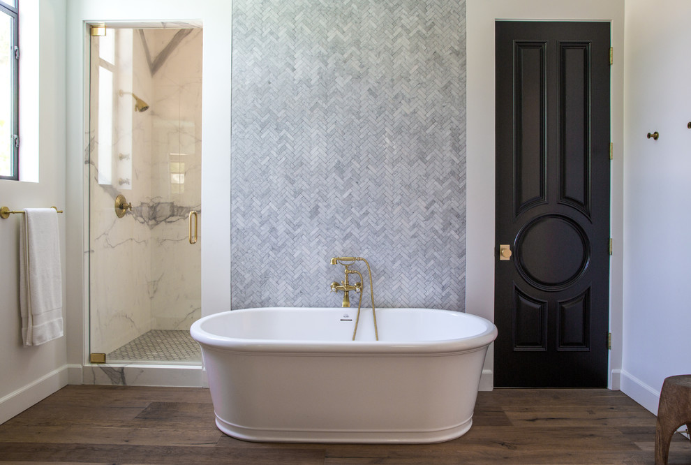 Идея дизайна: ванная комната в стиле неоклассика (современная классика) с отдельно стоящей ванной, угловым душем, плиткой из листового камня, белыми стенами, темным паркетным полом, коричневым полом и душем с распашными дверями