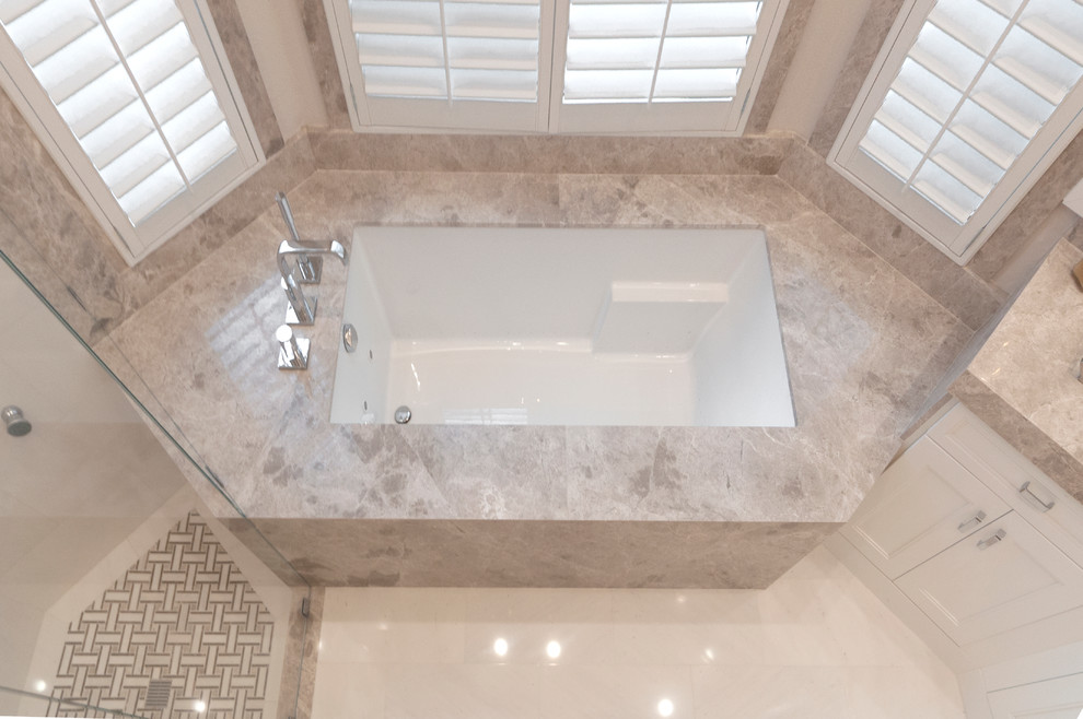 На фото: большая главная ванная комната в стиле модернизм с накладной раковиной, мраморной столешницей, гидромассажной ванной, угловым душем, бежевой плиткой, керамогранитной плиткой, бежевыми стенами и мраморным полом с