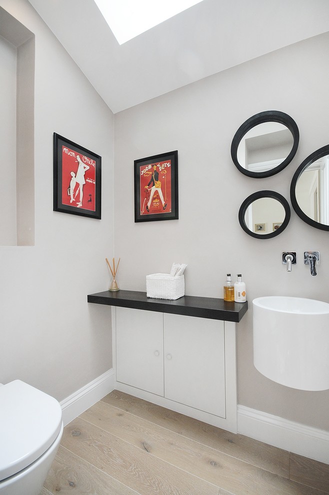 Modern bathroom in London with a wall-mounted sink, flat-panel cabinets and white cabinets.
