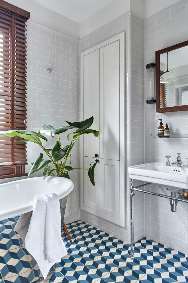 Inredning av ett klassiskt litet en-suite badrum, med luckor med infälld panel, skåp i mörkt trä, ett fristående badkar, keramikplattor, grå kakel, ett konsol handfat och vita väggar