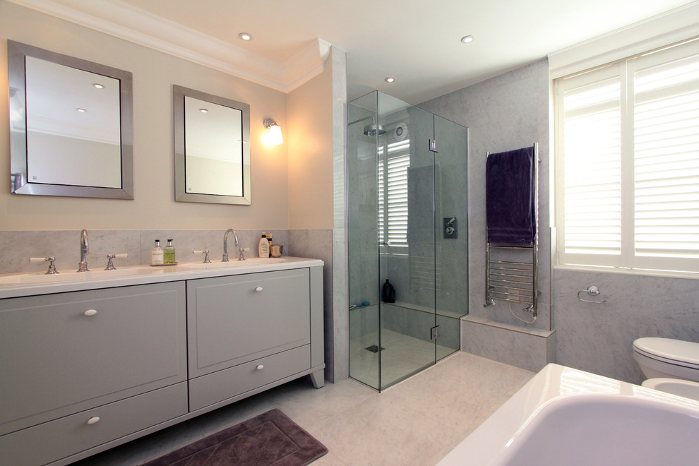 На фото: главная ванная комната в стиле неоклассика (современная классика) с фасадами с выступающей филенкой, серыми фасадами, душем без бортиков, серой плиткой и монолитной раковиной с