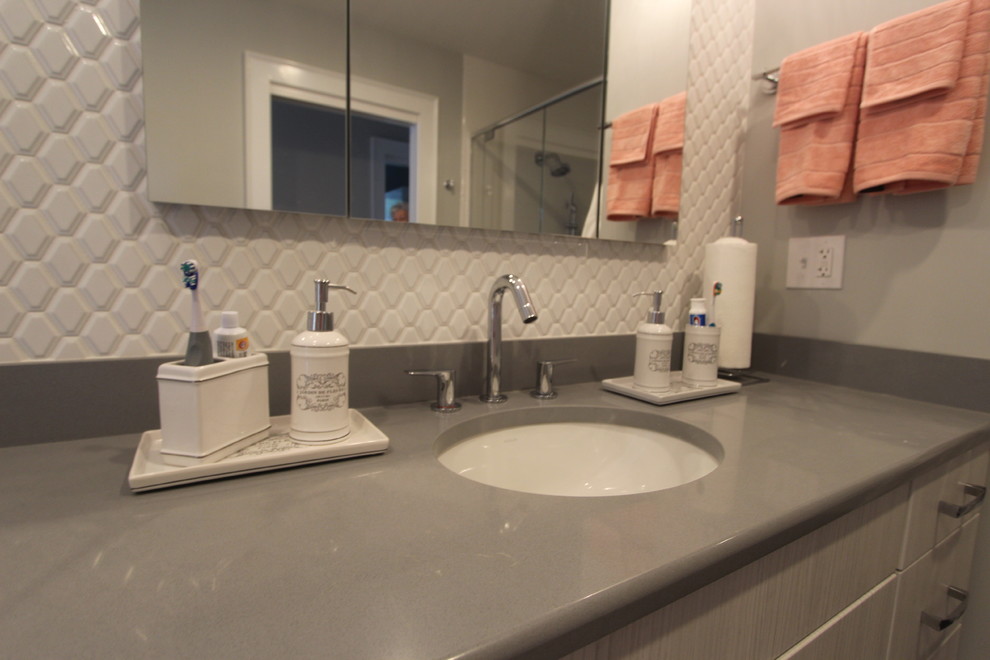 Modern inredning av ett mellanstort badrum, med släta luckor, vita skåp, en kantlös dusch, en toalettstol med separat cisternkåpa, vit kakel, keramikplattor, grå väggar, klinkergolv i porslin, ett undermonterad handfat, bänkskiva i kvarts, grått golv och dusch med gångjärnsdörr