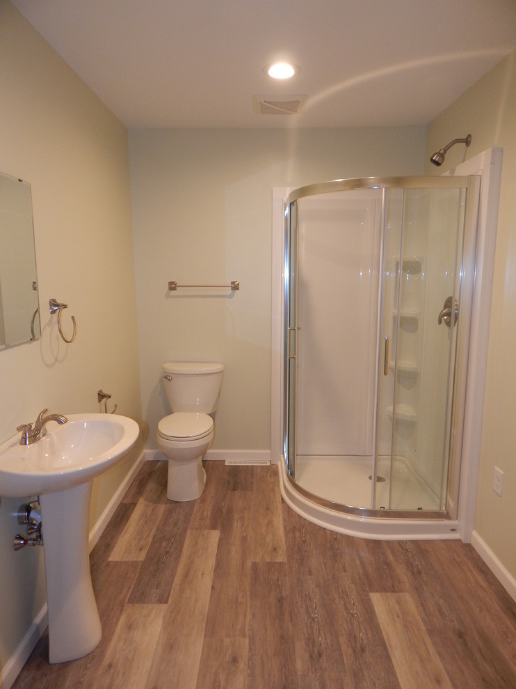 Cette photo montre une salle de bain chic de taille moyenne avec sol en stratifié, une douche d'angle, WC à poser, un mur blanc et un lavabo de ferme.