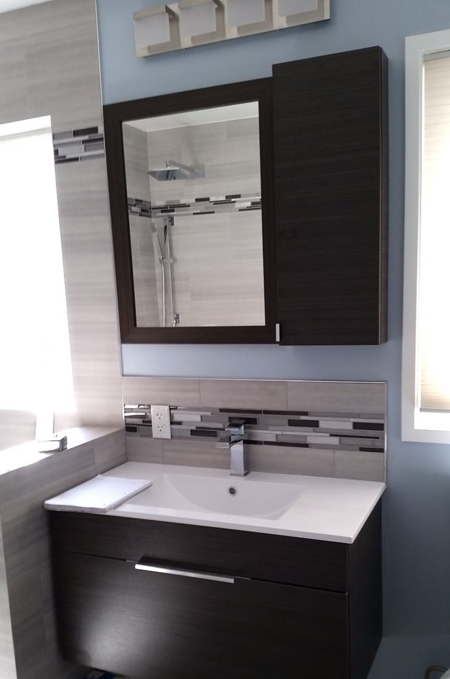 This is an example of a medium sized contemporary ensuite bathroom in Los Angeles with a corner shower, grey tiles, stone tiles, grey walls, light hardwood flooring and a built-in sink.