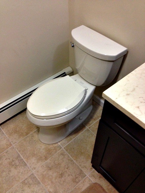Cette image montre un petit WC et toilettes design en bois foncé avec un lavabo encastré, un placard à porte shaker, un plan de toilette en granite, WC séparés, un carrelage beige, mosaïque, un mur beige et un sol en carrelage de porcelaine.