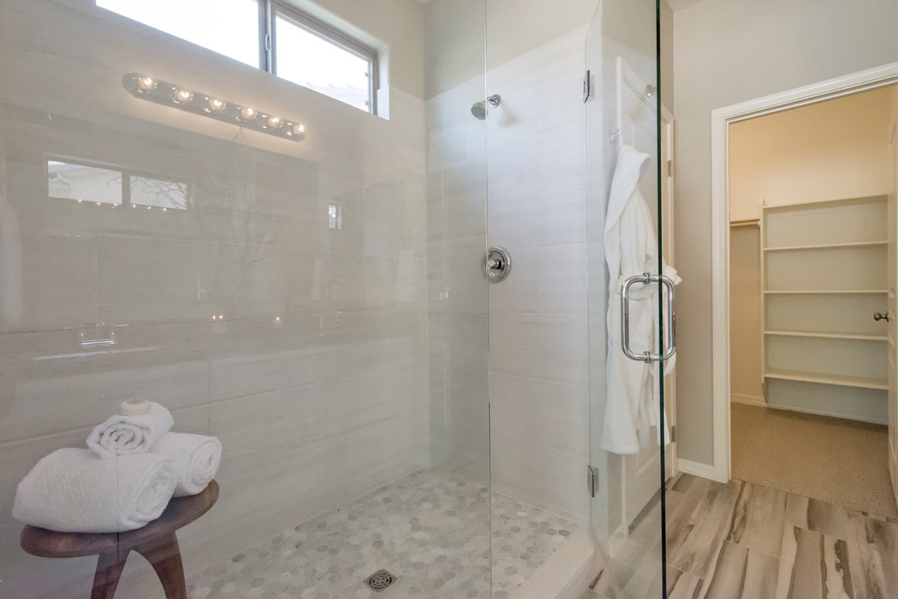 Photo of a medium sized contemporary ensuite bathroom in Phoenix with raised-panel cabinets, white cabinets, an alcove shower, a one-piece toilet, grey tiles, porcelain tiles, grey walls, porcelain flooring, a built-in sink, quartz worktops, grey floors and a hinged door.