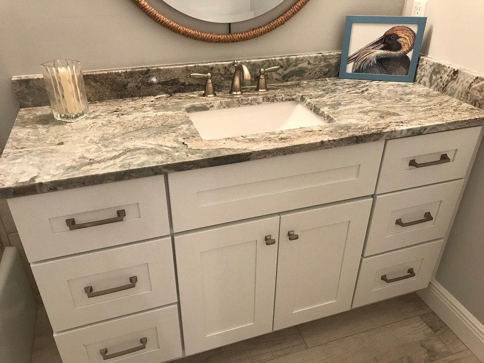 Immagine di una stanza da bagno stile marino con ante bianche, pavimento in gres porcellanato, lavabo sottopiano, top in granito e top beige