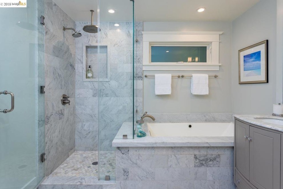 Klassisk inredning av ett mellanstort grå grått en-suite badrum, med luckor med upphöjd panel, grå skåp, ett platsbyggt badkar, en hörndusch, en toalettstol med separat cisternkåpa, grå kakel, marmorkakel, grå väggar, marmorgolv, ett undermonterad handfat, marmorbänkskiva, grått golv och dusch med gångjärnsdörr