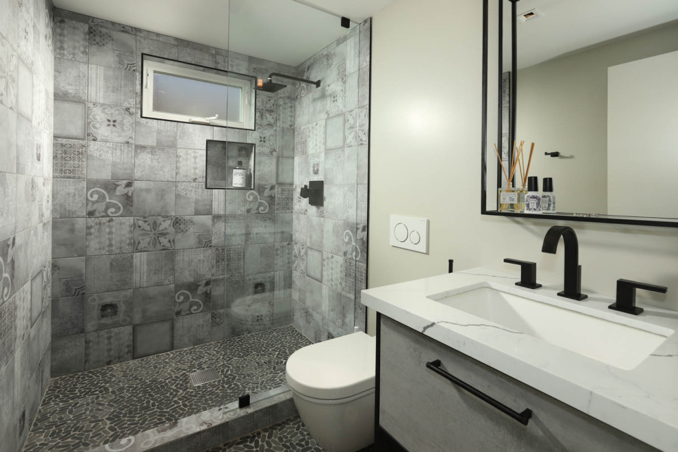Large urban 3/4 gray tile and porcelain tile mosaic tile floor and gray floor bathroom photo in Los Angeles with flat-panel cabinets, gray cabinets, a wall-mount toilet, gray walls, quartz countertops and multicolored countertops