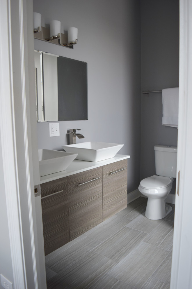 Mid-sized trendy 3/4 vinyl floor and gray floor bathroom photo in Chicago with flat-panel cabinets, medium tone wood cabinets, a two-piece toilet, gray walls, a vessel sink and quartz countertops