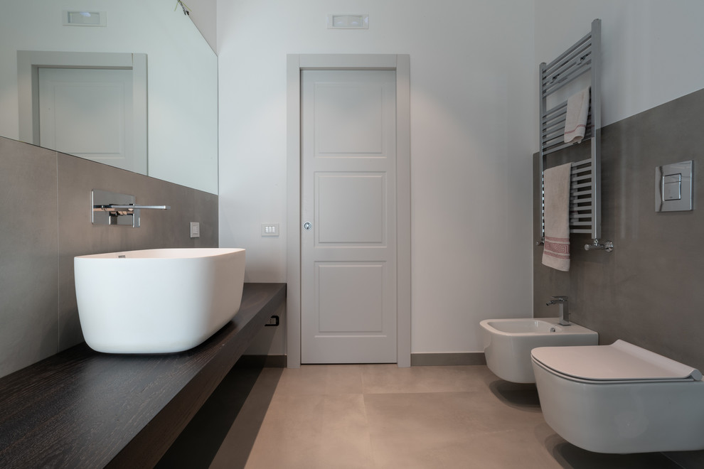 Photo of a contemporary bathroom in London with grey tiles, white walls, a vessel sink, wooden worktops, grey floors and brown worktops.