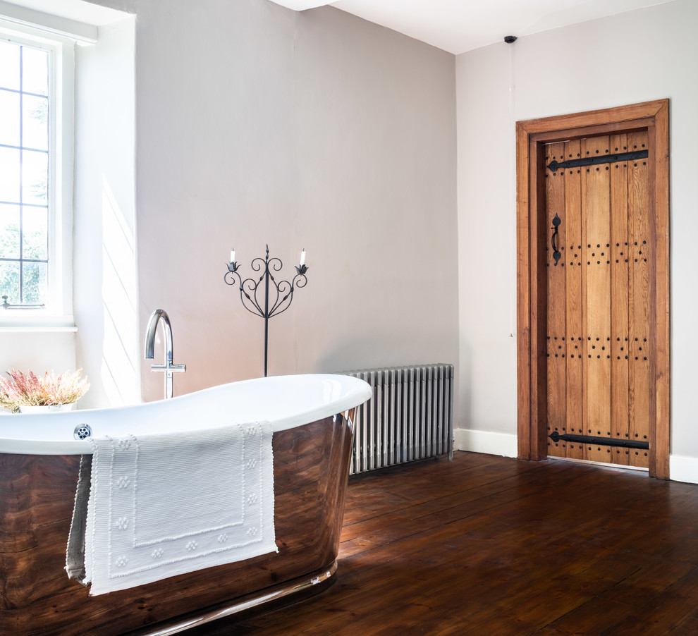 Réalisation d'une salle de bain tradition avec une baignoire indépendante, un mur gris, un sol en bois brun et un sol marron.