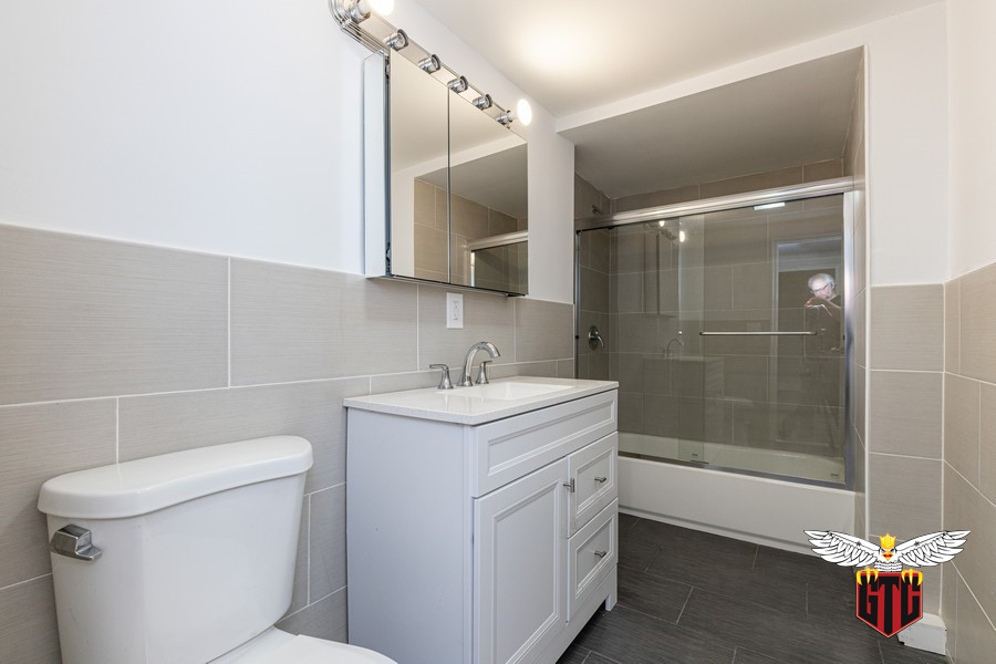 Bathroom - small modern master beige tile and porcelain tile porcelain tile, black floor and single-sink bathroom idea in Philadelphia with raised-panel cabinets, white cabinets, a one-piece toilet, beige walls, a drop-in sink, quartzite countertops, white countertops and a freestanding vanity