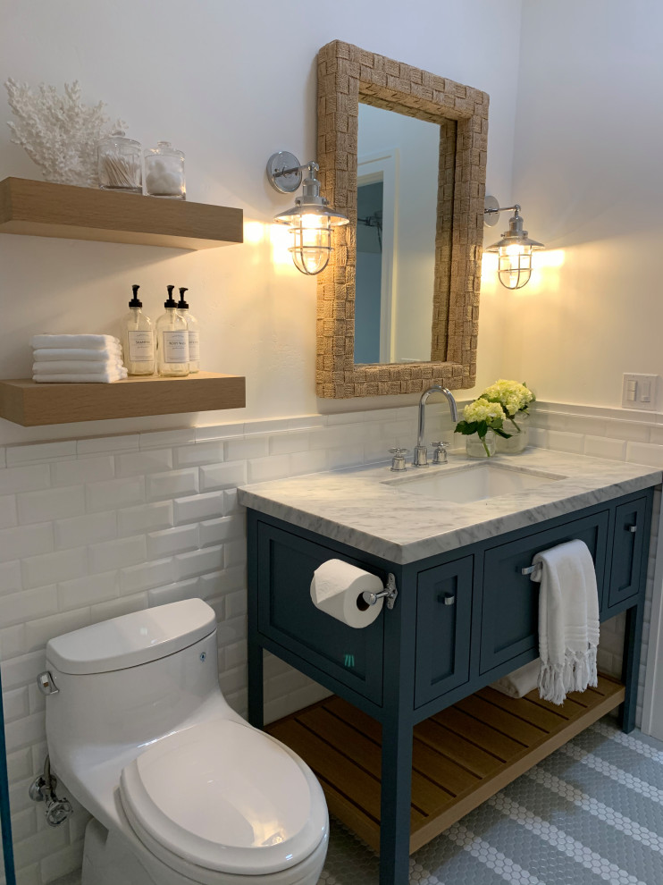 Exempel på ett litet maritimt grå grått badrum med dusch, med skåp i shakerstil, blå skåp, en toalettstol med hel cisternkåpa, vit kakel, tunnelbanekakel, vita väggar, klinkergolv i porslin, ett undermonterad handfat, marmorbänkskiva, grått golv och dusch med gångjärnsdörr
