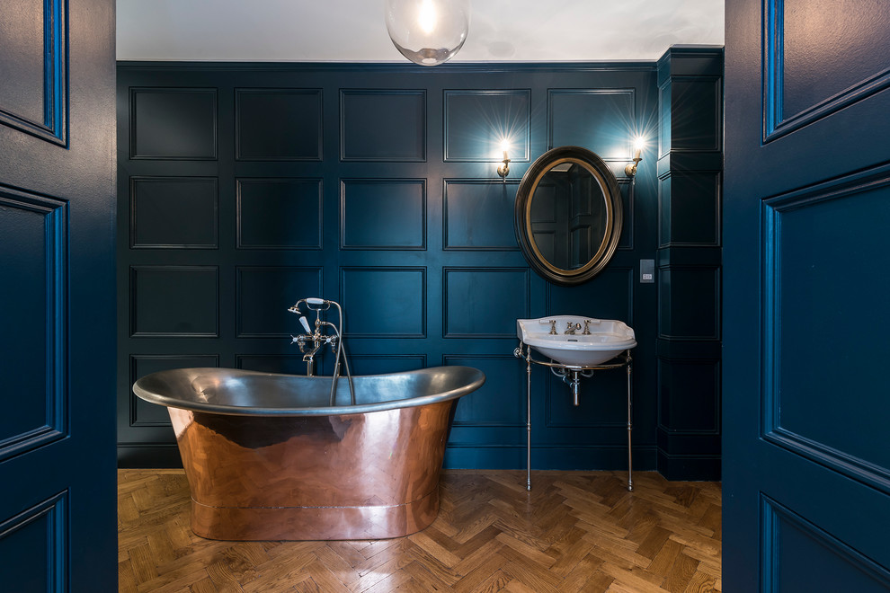 Imagen de cuarto de baño principal tradicional renovado grande con lavabo suspendido, bañera exenta, combinación de ducha y bañera, sanitario de una pieza, paredes azules y suelo de madera clara