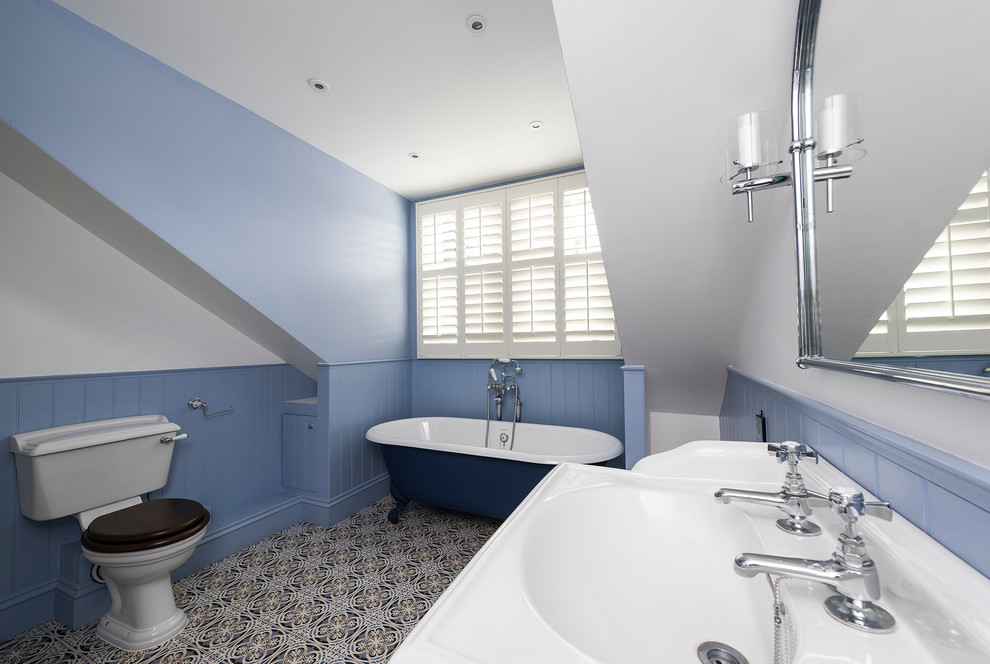 This is an example of a large traditional ensuite bathroom in London with a wall-mounted sink, a freestanding bath, a shower/bath combination, a one-piece toilet, multi-coloured tiles, ceramic flooring and blue walls.