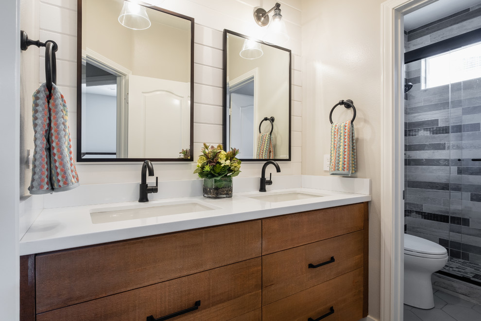 Example of a mid-sized cottage master gray tile gray floor bathroom design in Los Angeles with flat-panel cabinets, medium tone wood cabinets, a one-piece toilet, gray walls, an undermount sink, quartz countertops and white countertops